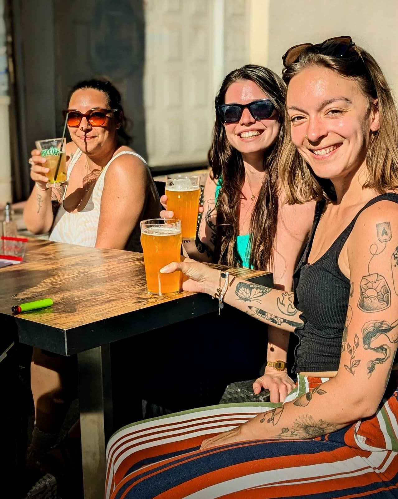 Trois amies attablées en terrasse, verres de bière blonde